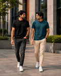 Two men walking outdoors wearing plain crew neck T-shirts for men, one in black with black jeans and the other in teal blue with beige chinos paired with white sneakers for a casual everyday look.